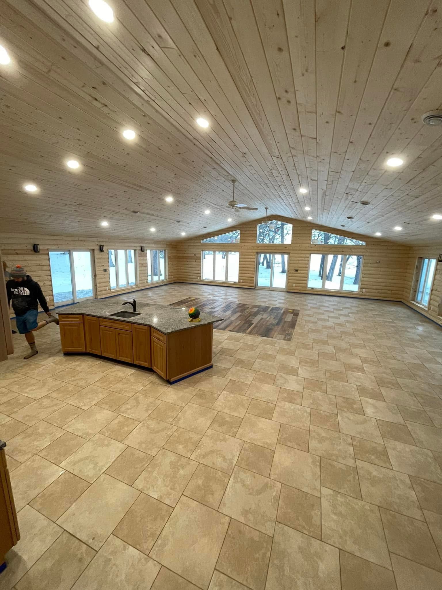 Spacious empty hall with tiled floor, wood-paneled counter, bright ceiling lights, and large windows.