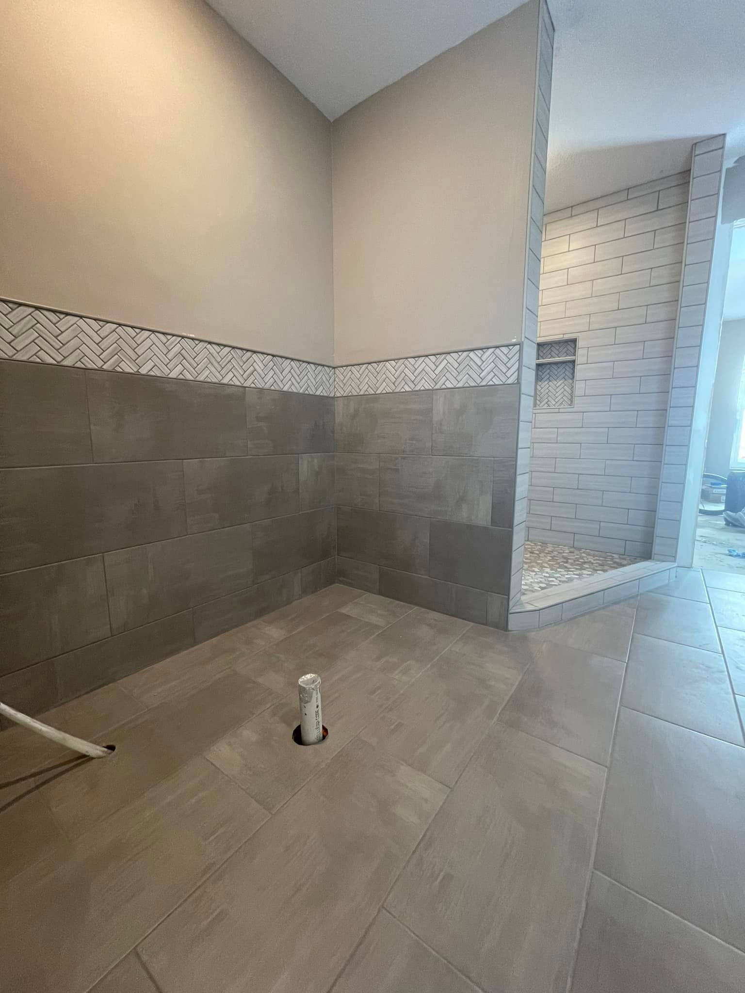 Empty tiled bathroom under construction with beige walls and a doorway to a shower area.
