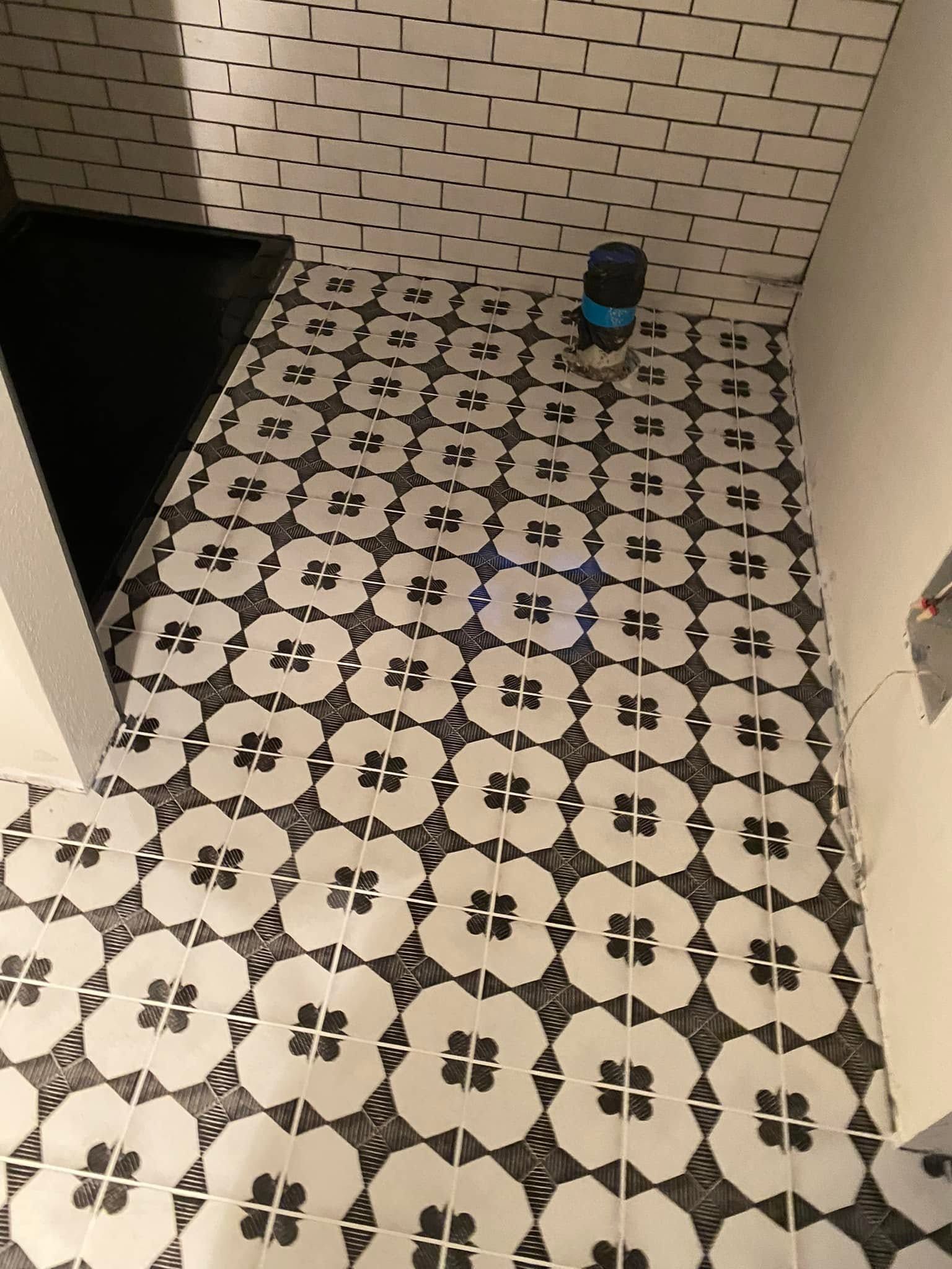 Black-and-white patterned bathroom floor with a small blue container in the back corner