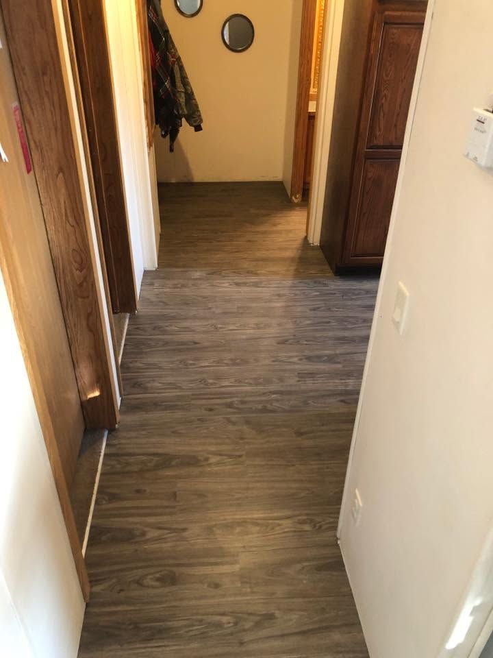 Narrow hallway with wood-look flooring, beige walls, and doorways on both sides