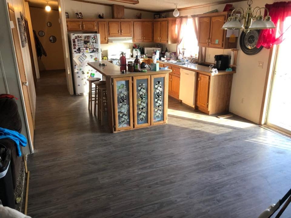Spacious kitchen with wood cabinets, center island, refrigerator, and dark wood floor.