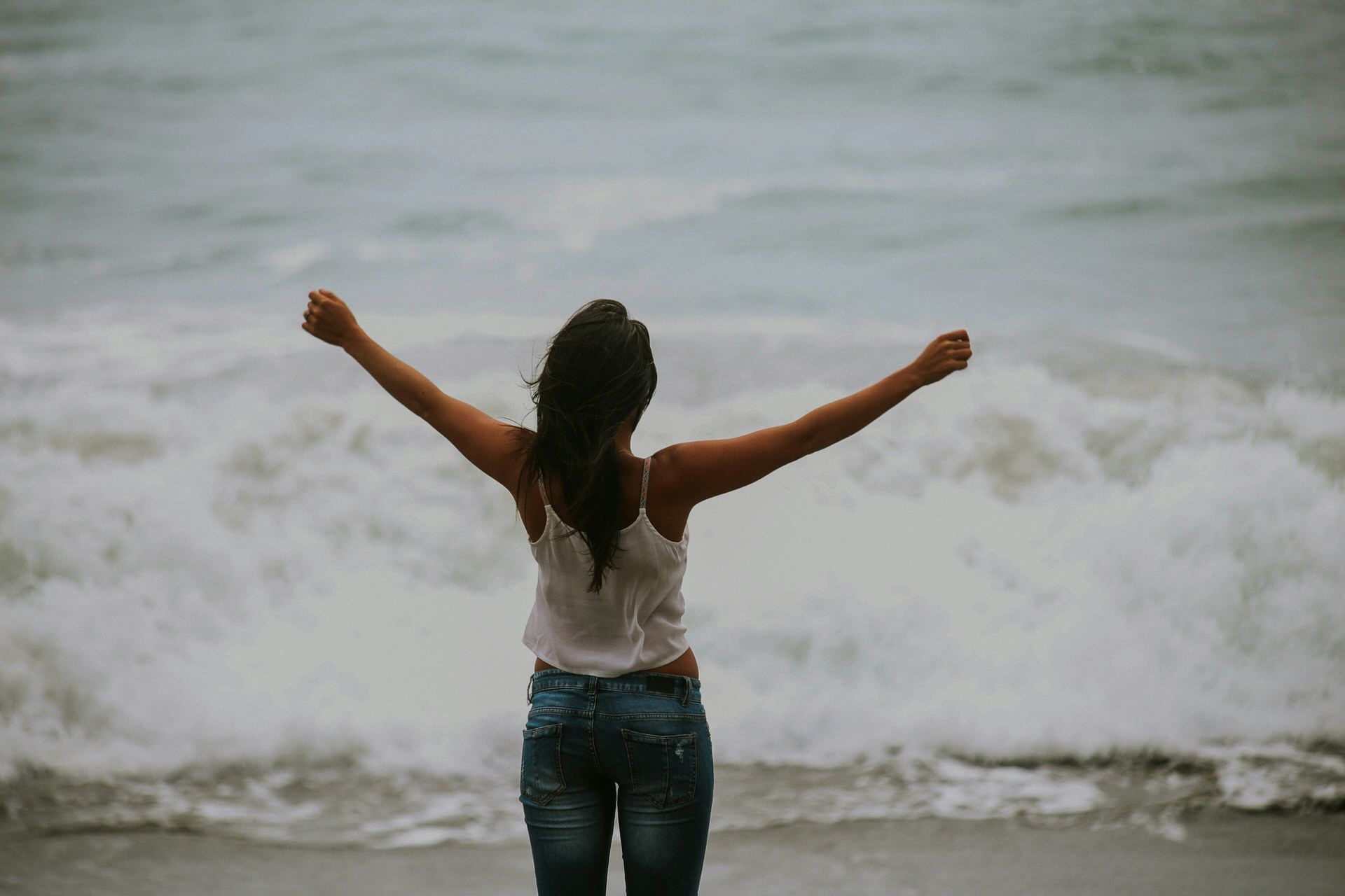 Looking at the waves crashing on the beach with my arms raised above my head.