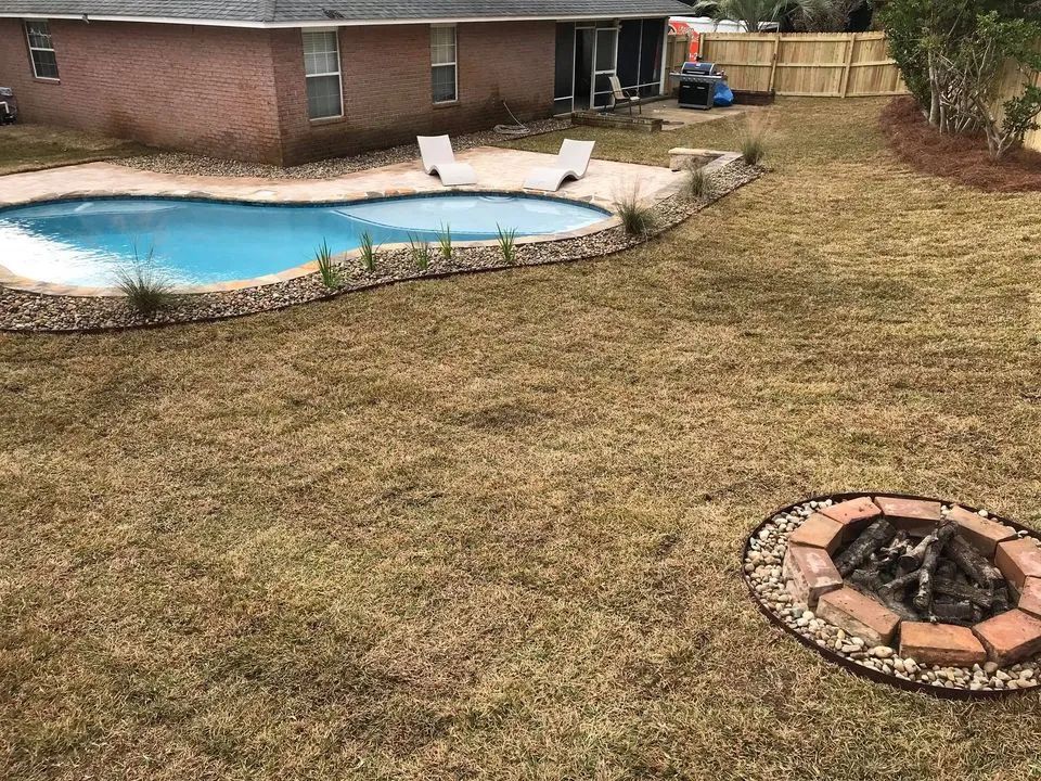 A backyard with a swimming pool and a fire pit.