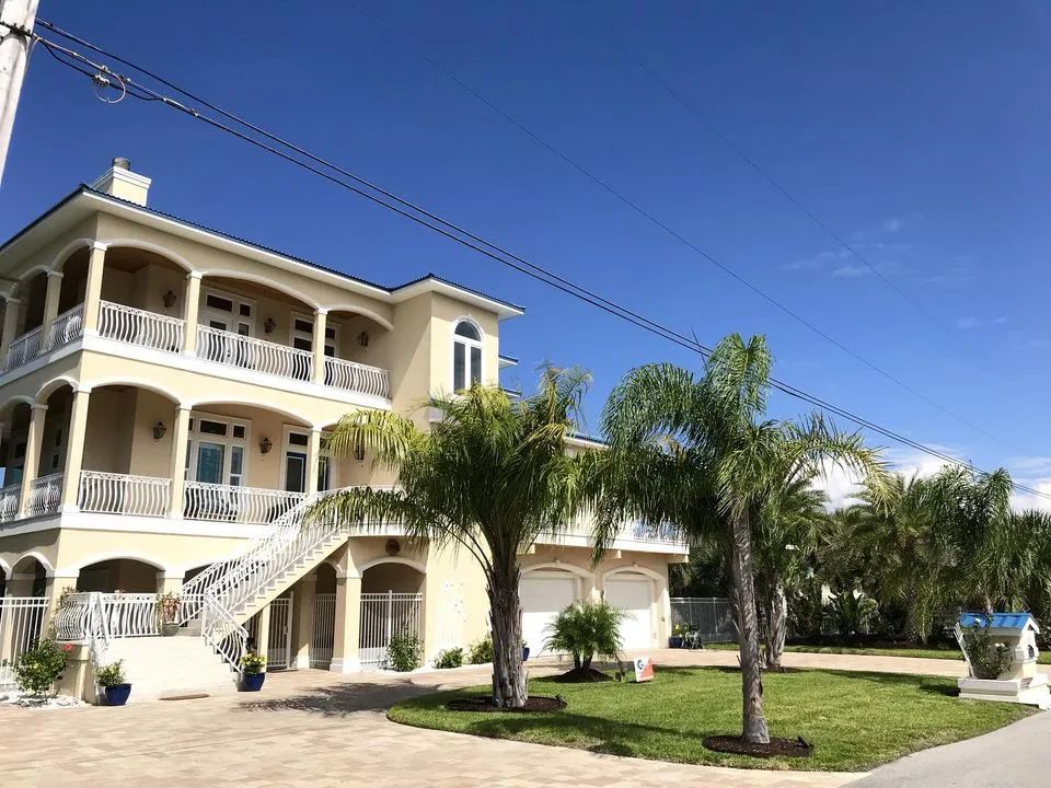 A large house with a lot of balconies and palm trees in front of it.