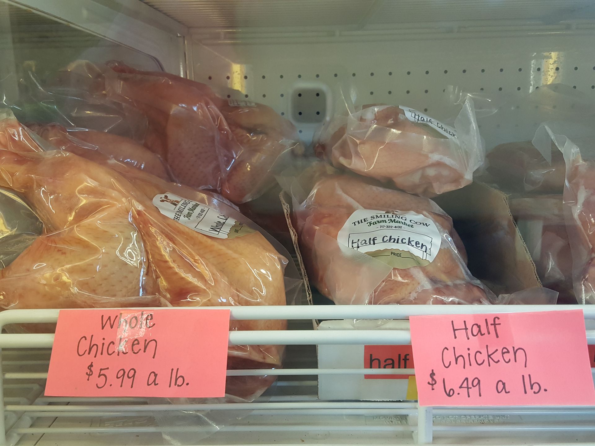 A refrigerator filled with chicken and a sign that says half chicken