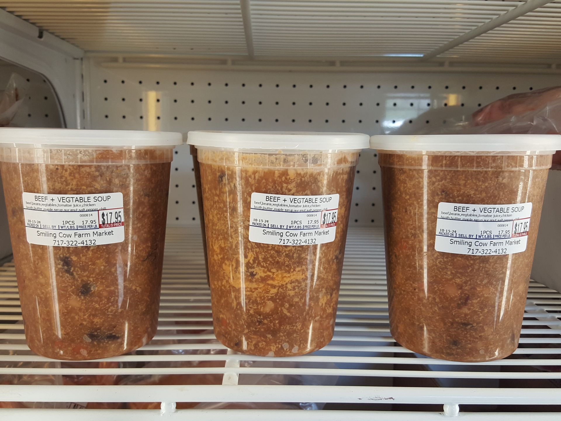 Three cups of food are sitting on a shelf in a refrigerator