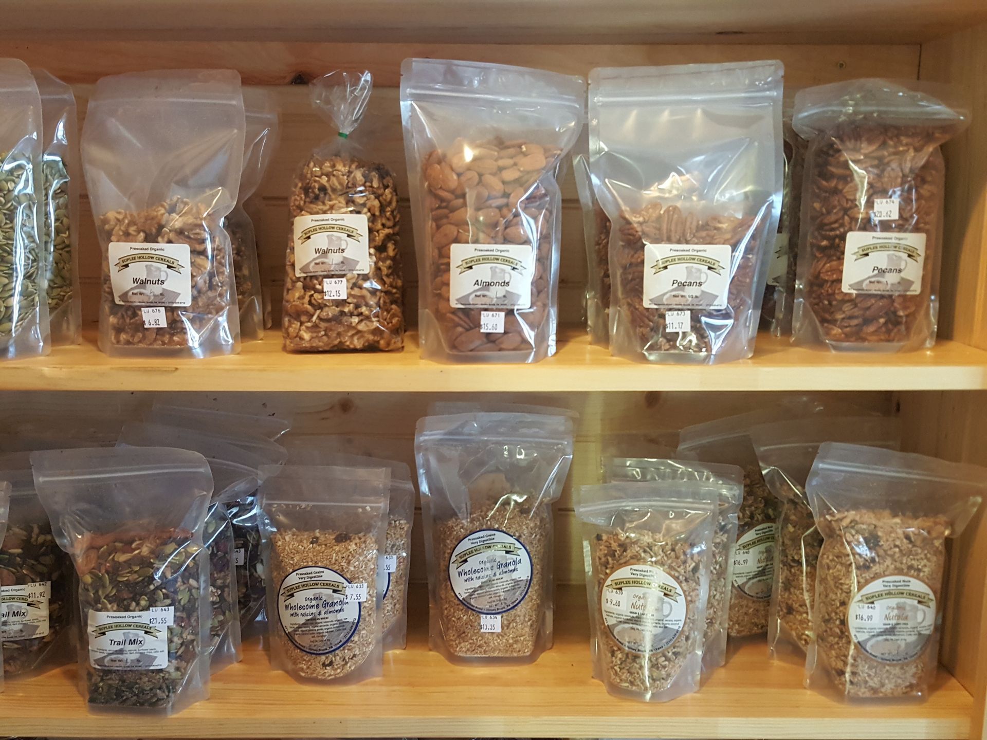 A shelf filled with bags of granola on a wooden shelf.
