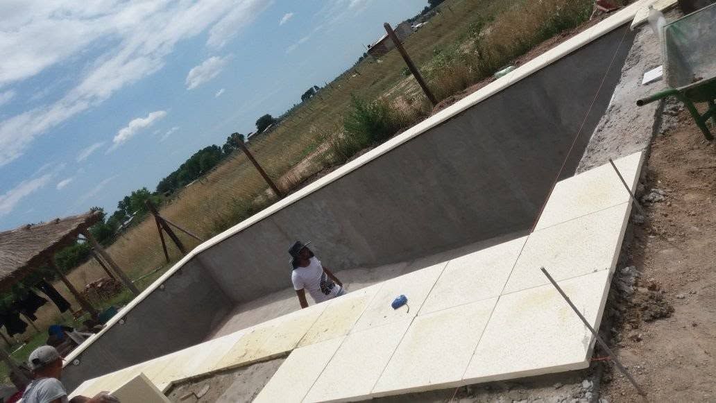 Canal de drenaje de hormigón en pendiente al aire libre, con una persona de pie cerca de la parte inferior y un objeto azul en la pendiente.