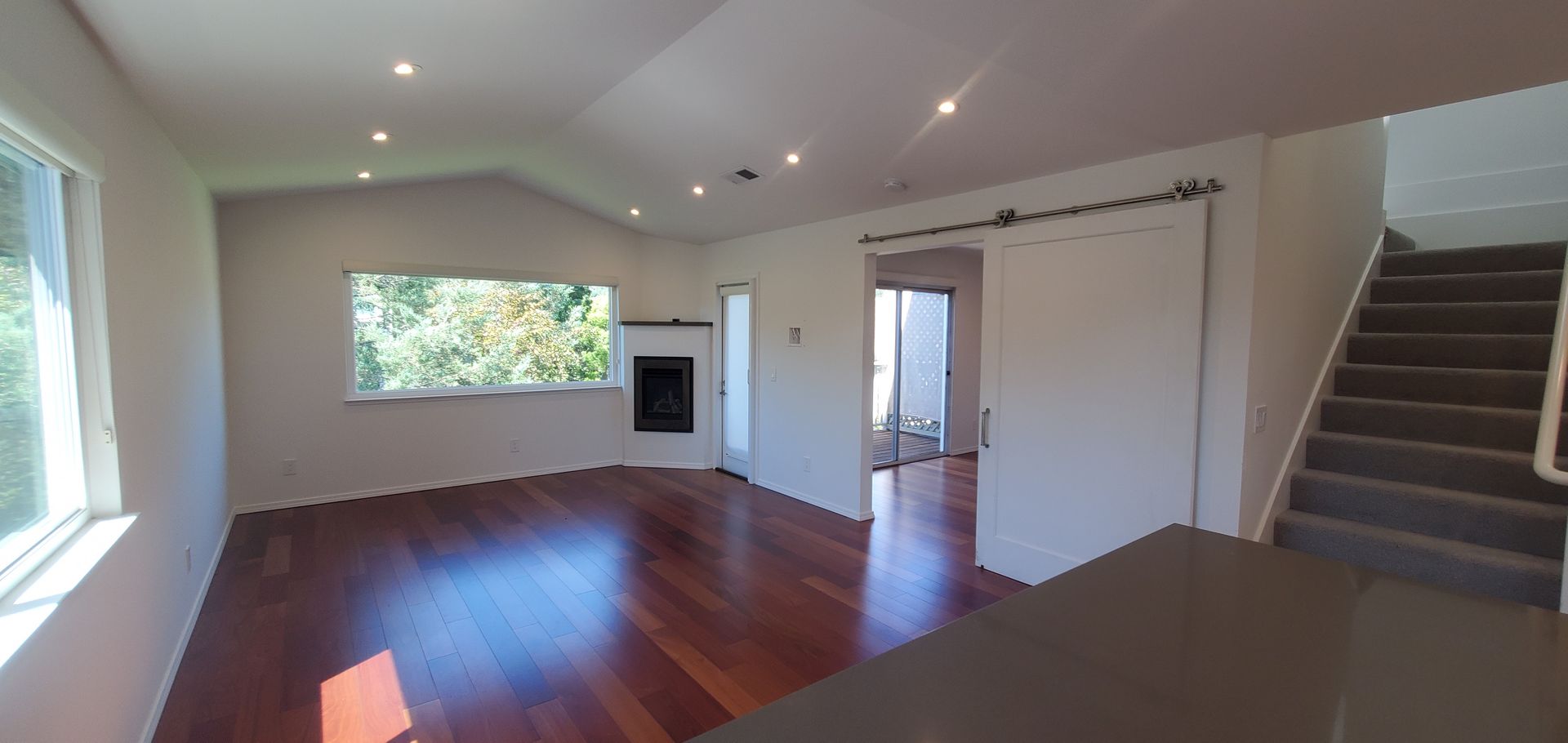 An empty living room with hardwood floors , a fireplace and stairs.