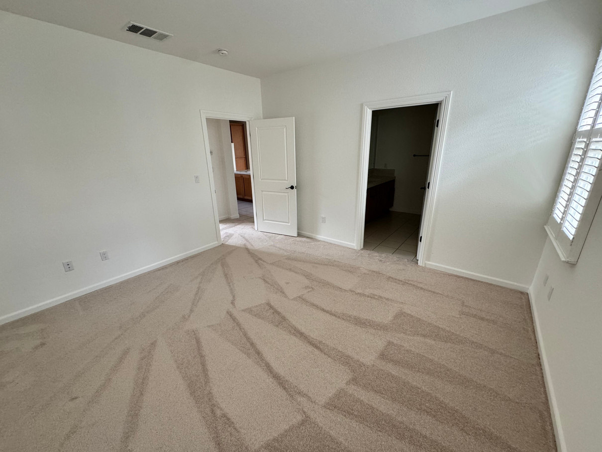 An empty bedroom with a carpeted floor and white walls.
