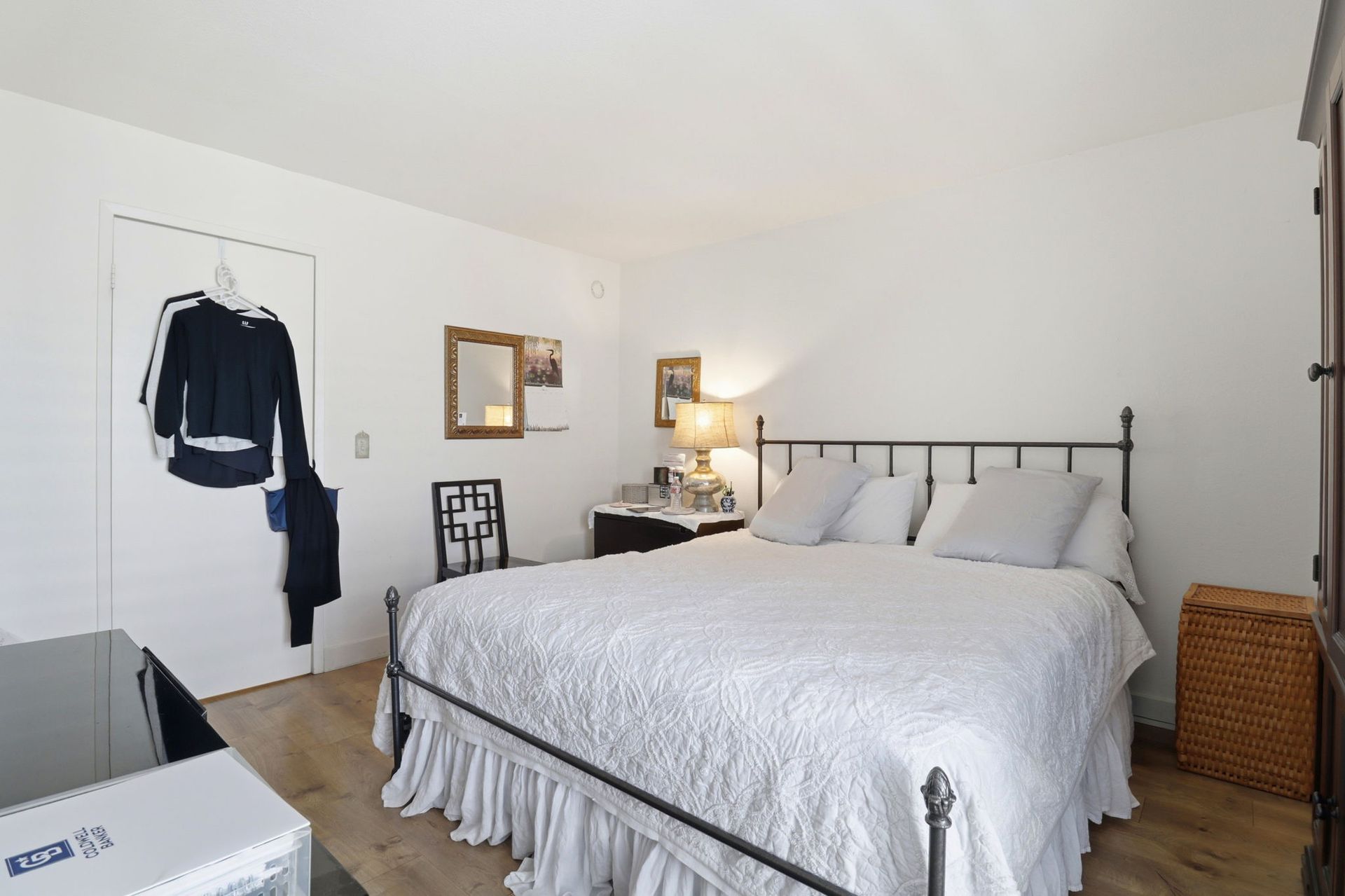 Cozy bedroom with a metal bed frame, white bedding, and a wicker basket by the wall.