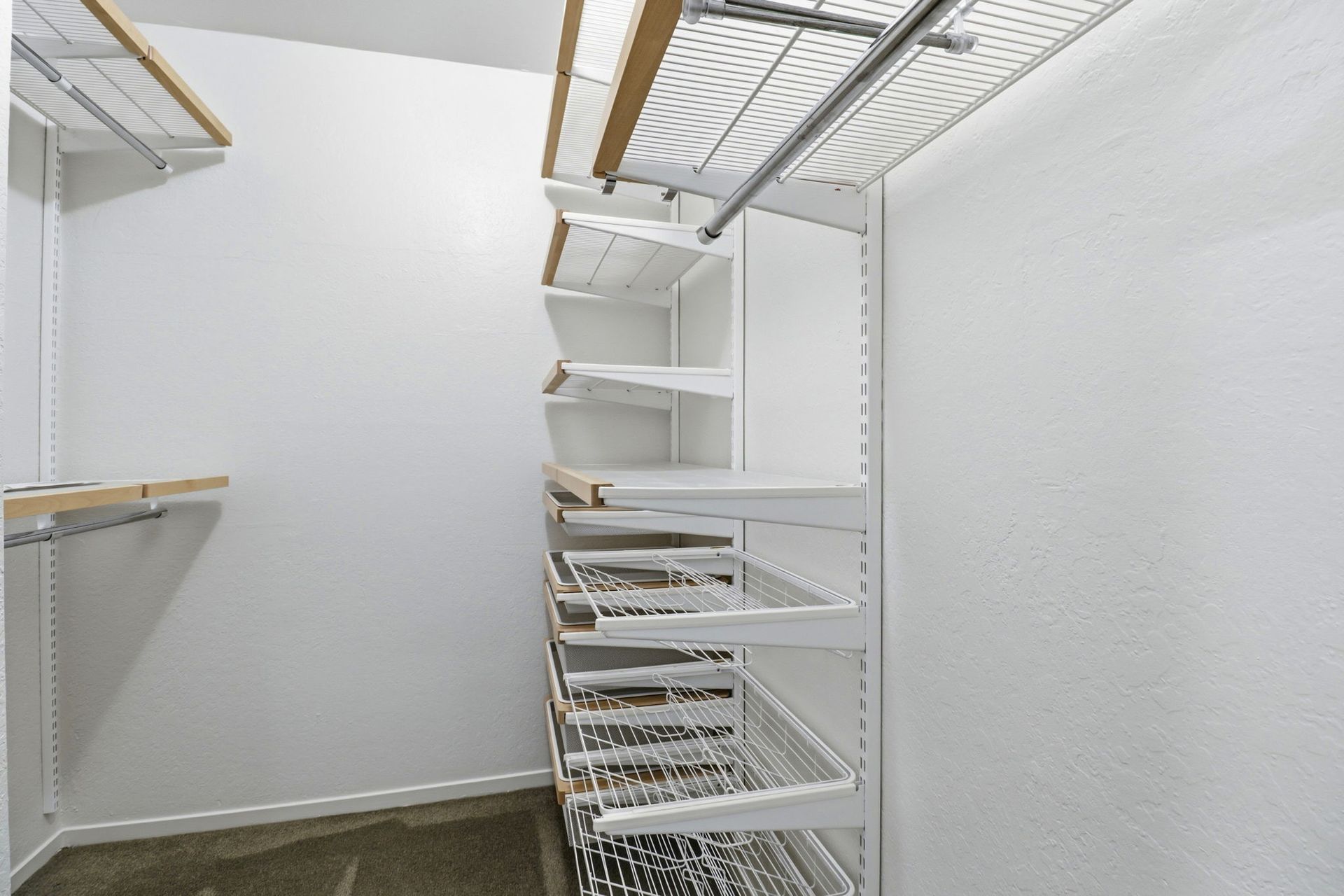 Empty white walk-in closet with wire shelving and hanging rods.