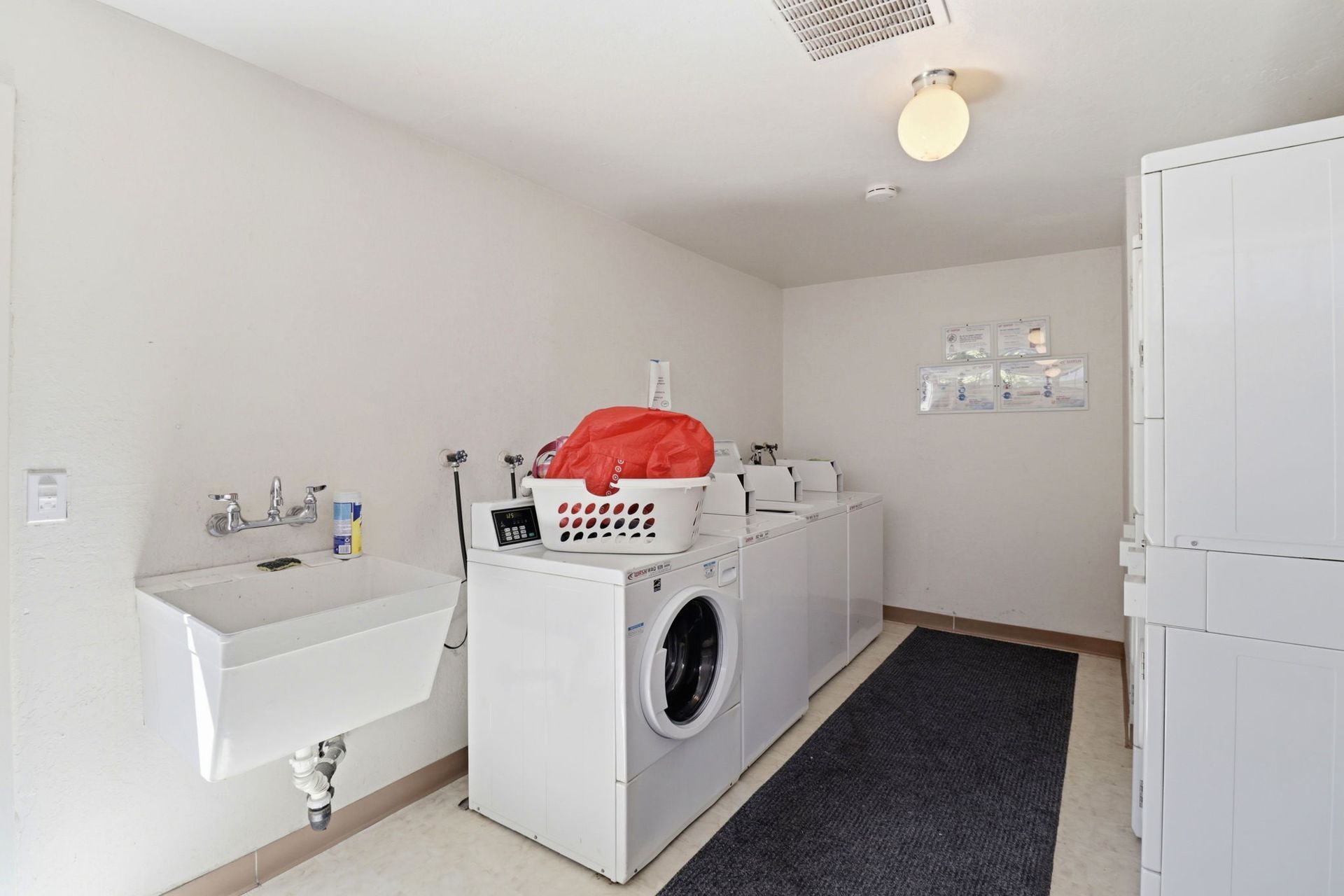 Laundry room with washer, utility sink, storage cabinets, and laundry baskets
