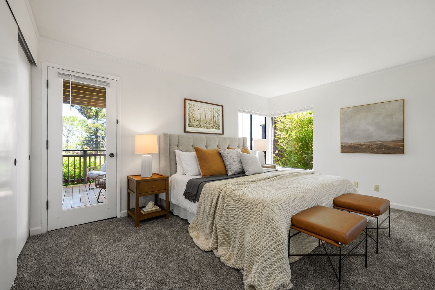 Bright bedroom with a made bed, bedside lamp, balcony door, and neutral decor