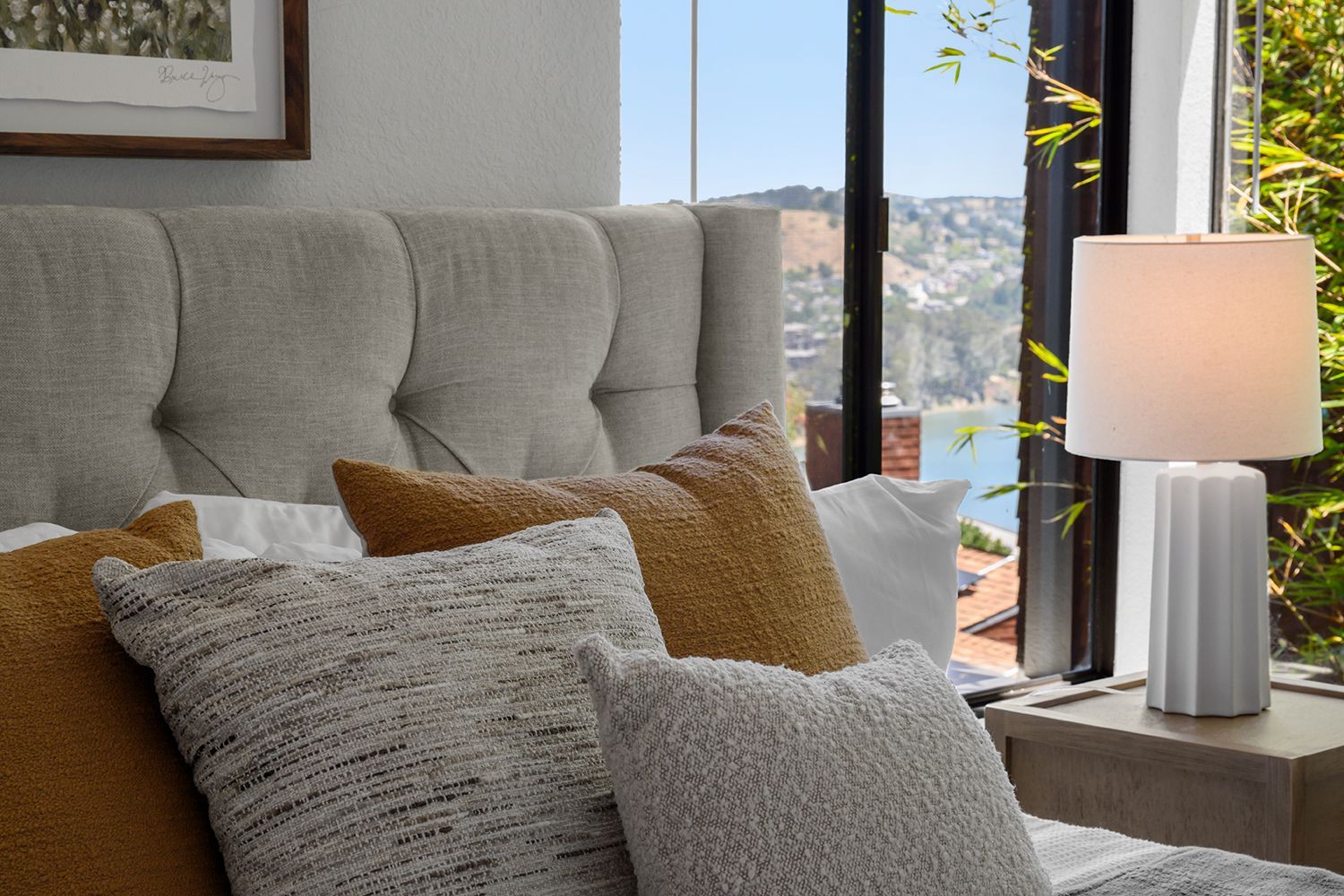 Cozy living room corner with tufted sofa, textured pillows, and a lit table lamp by a window
