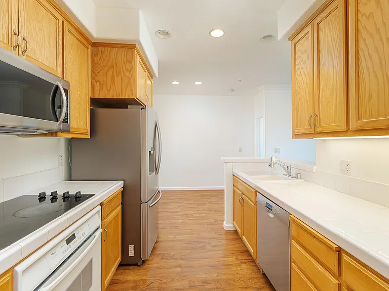 Kitchen with wooden cabinets, stainless steel appliances, and white countertops.