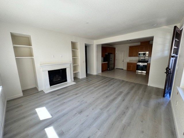 A living room with a fireplace and a kitchen in the background