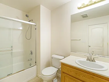 Bathroom with white fixtures, beige walls, and light wood vanity.