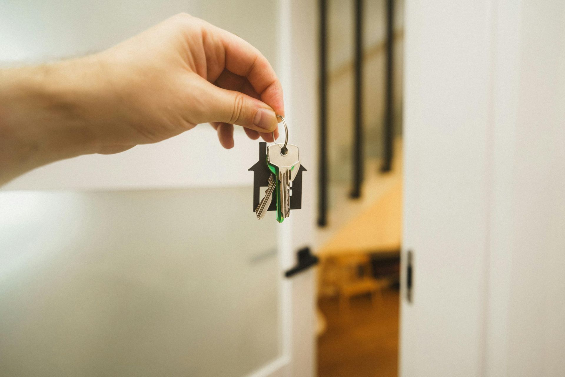 Hand holding a set of house keys in front of an open door