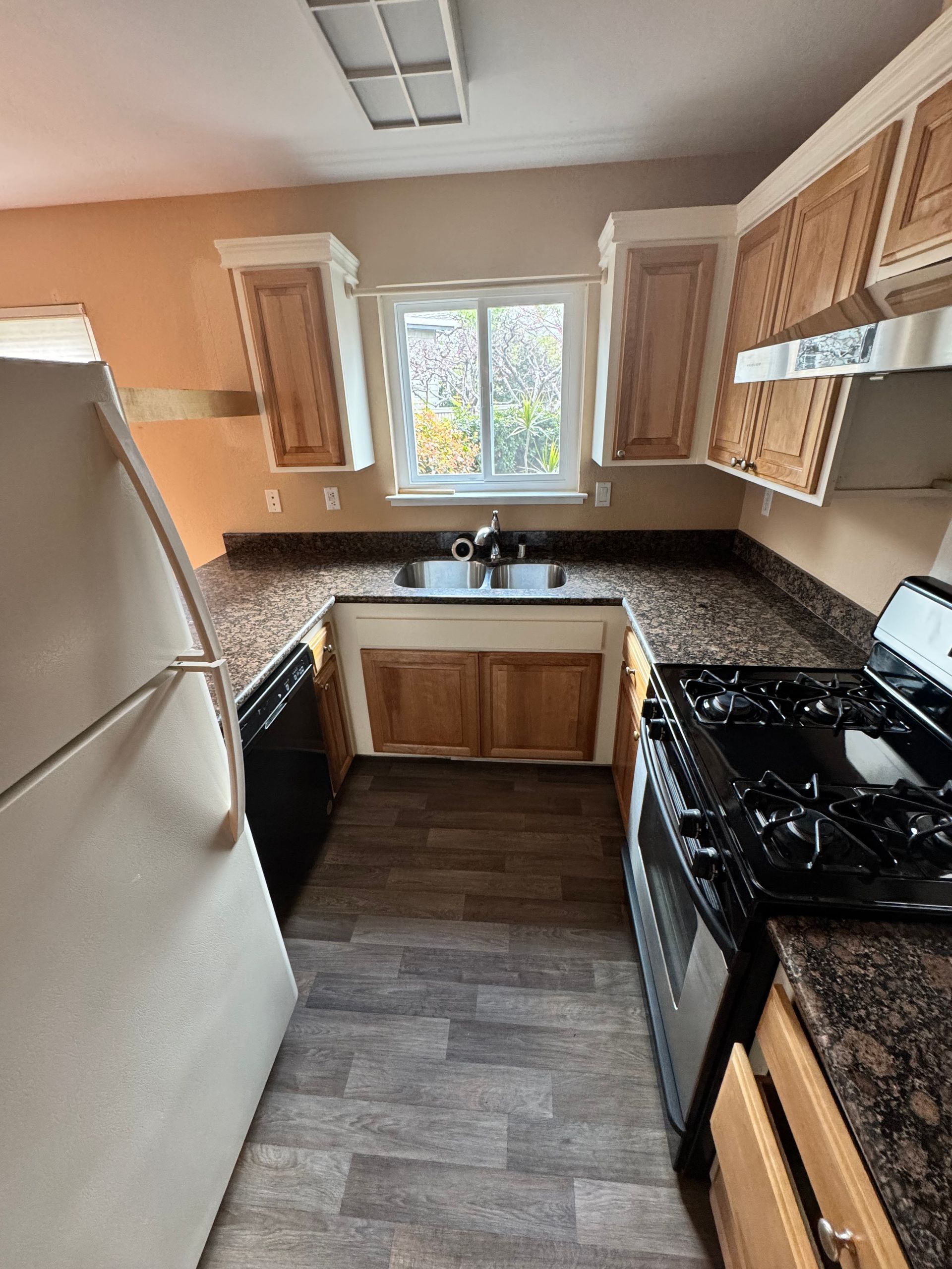 A kitchen with a refrigerator , stove , dishwasher , sink and window.