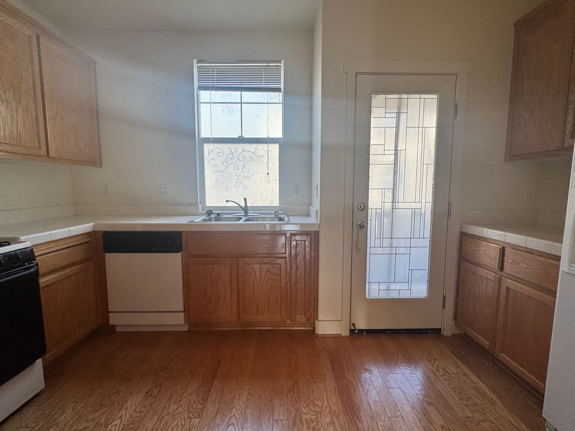 Kitchen with wooden cabinets, a sink under a window, and a glass-paneled door.