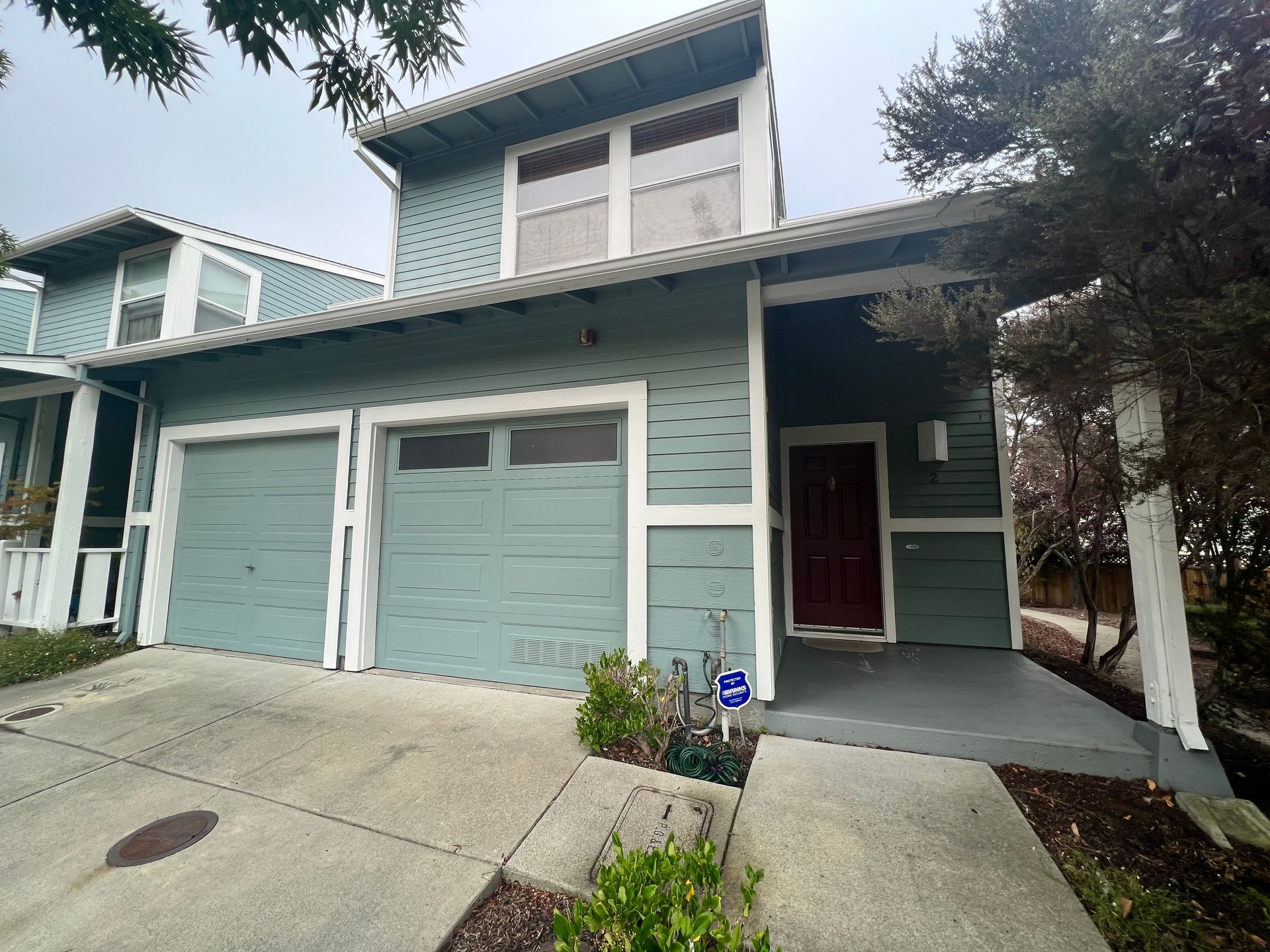 A blue house with three garage doors and a red door.