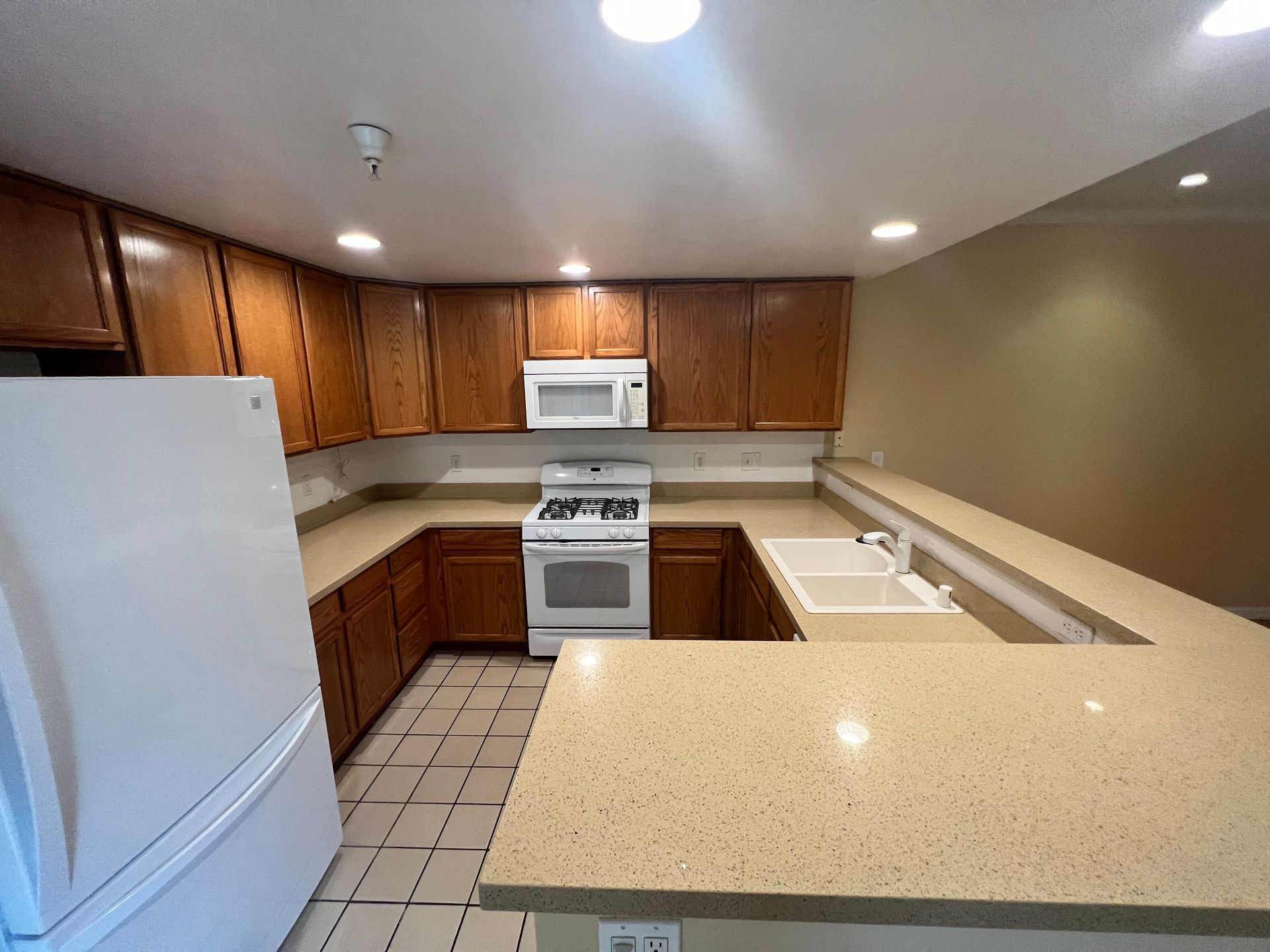A kitchen with a refrigerator , stove , microwave and sink.