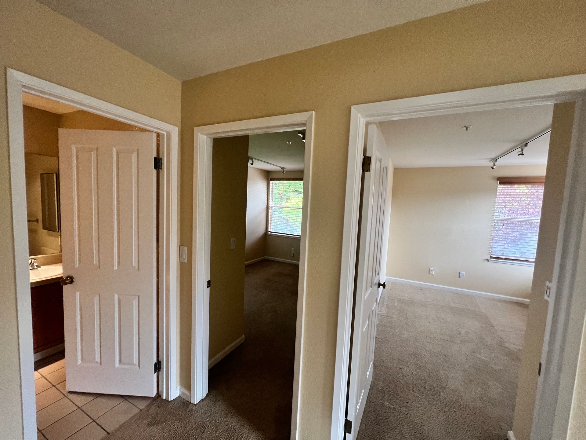 A hallway in a house leading to a bedroom and a bathroom.
