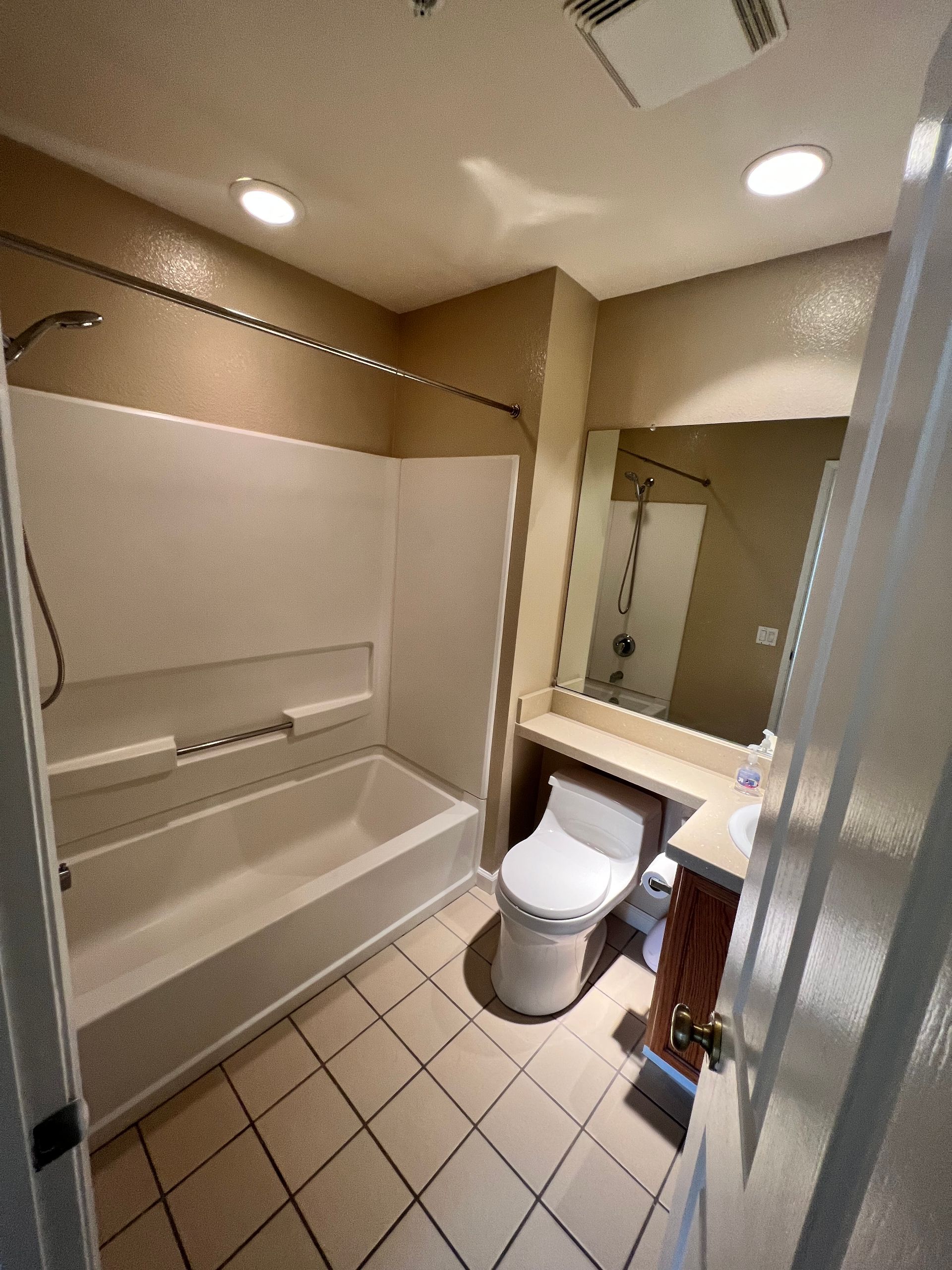 A bathroom with a toilet , tub , shower and mirror.