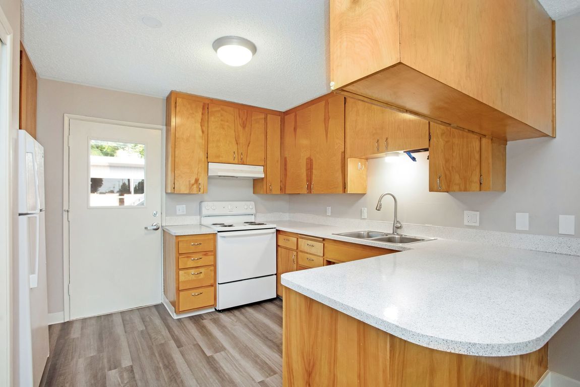 An empty kitchen with wooden cabinets and a sink
