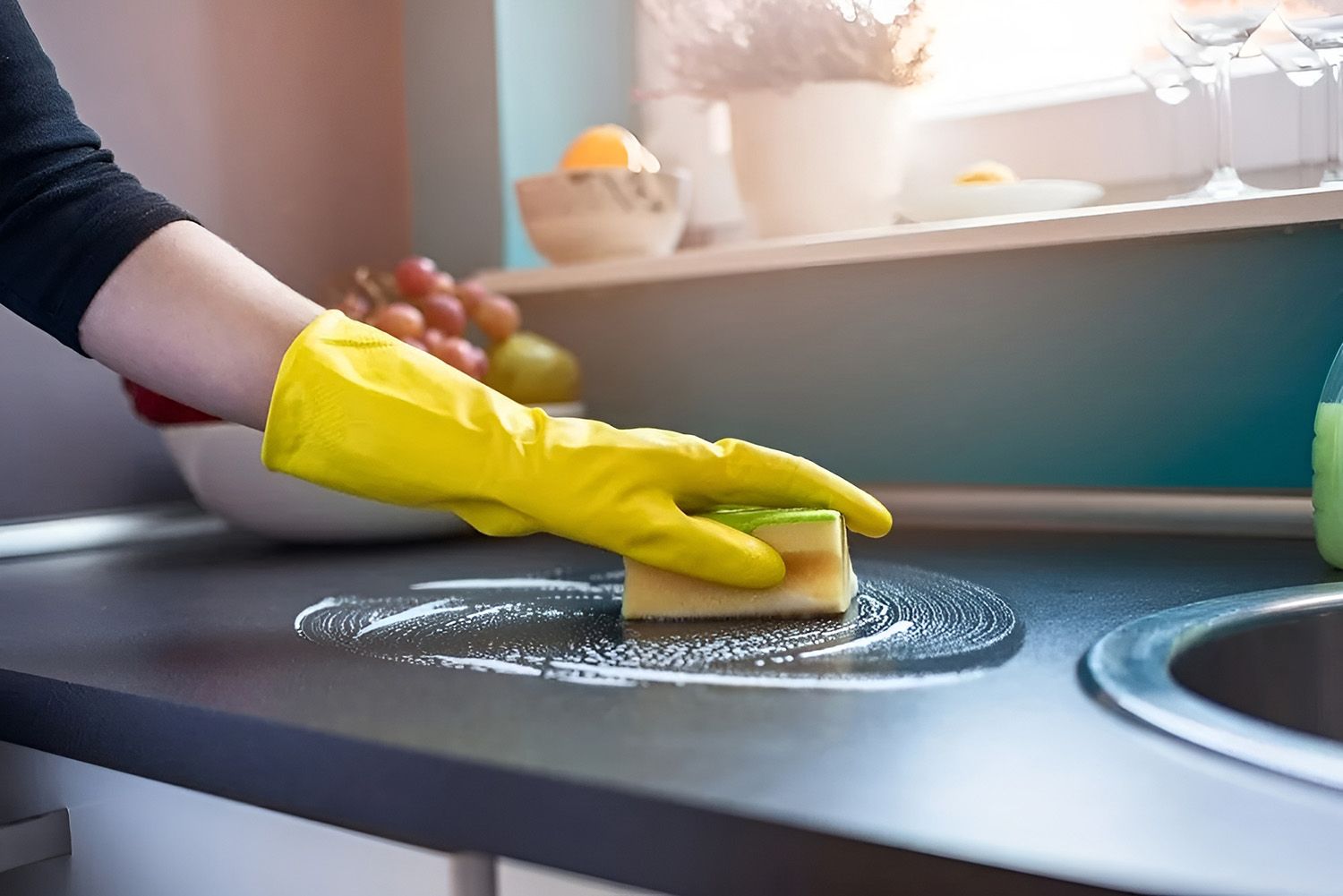 Hand in Yellow Glove Cleaning Kitchen Counter with Sponge