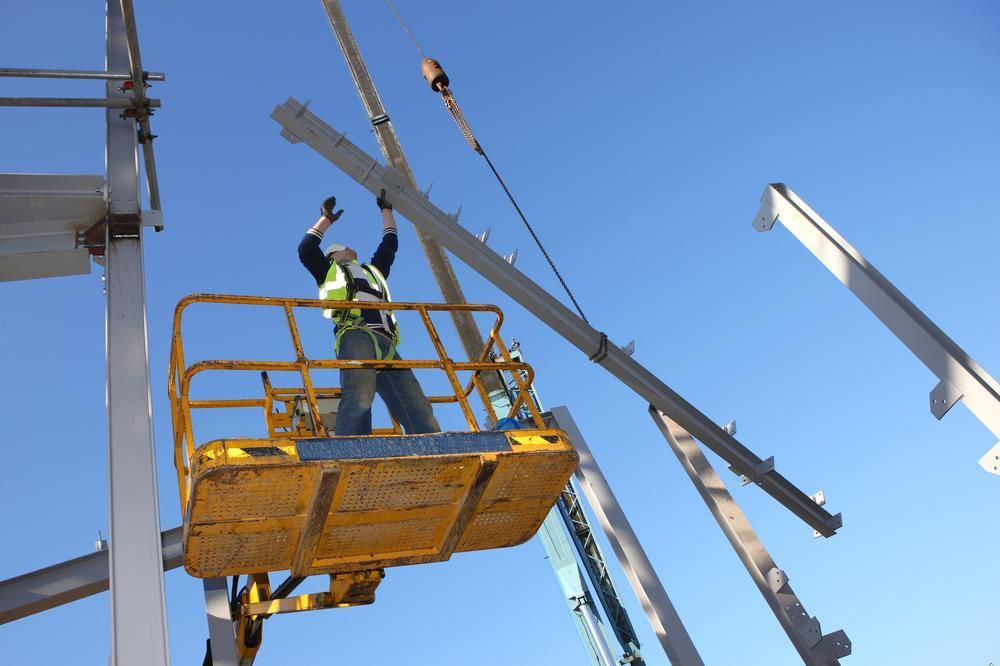 A Construction Worker Is Standing in A Yellow Lift — AMAC Cranes in Coolum Beach, QLD