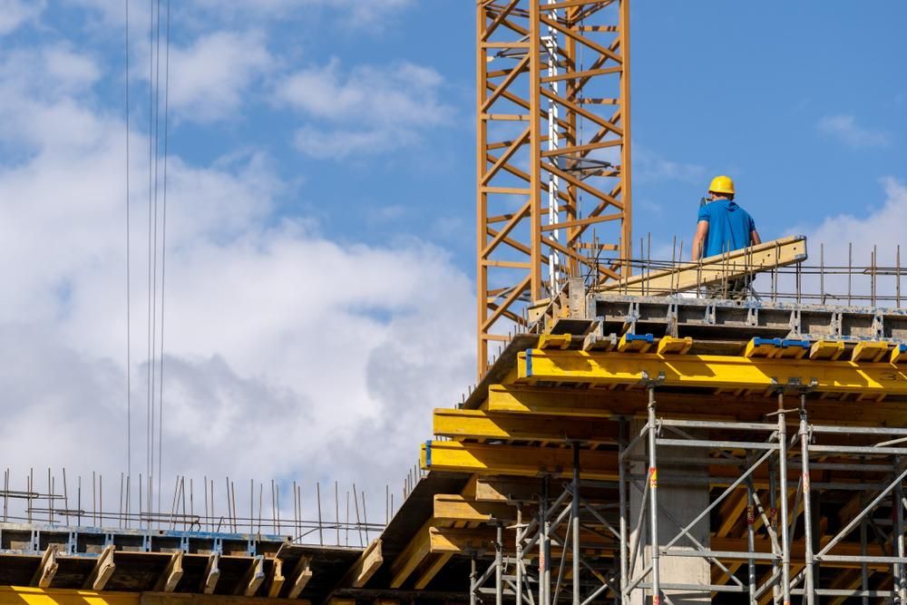 A Construction Worker Is Standing on Top of A Building Under Construction — AMAC Cranes in Coolum Beach, QLD