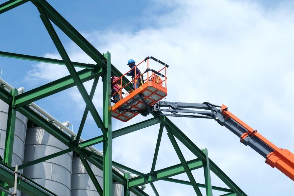A Man Is Sitting in A Bucket on A Crane — AMAC Cranes in Coolum Beach, QLD