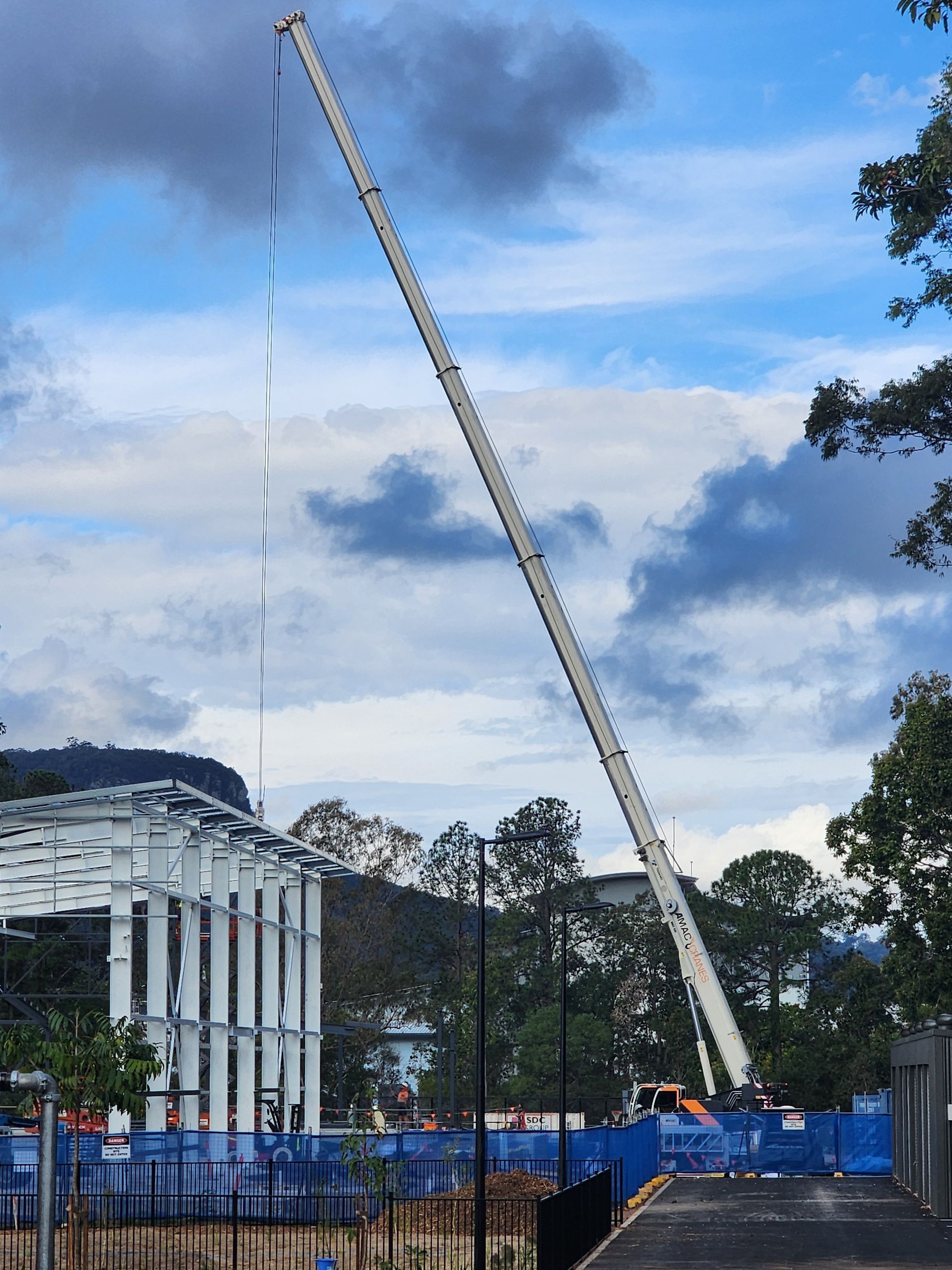 A Red Crane Is Against a Blue Sky with Clouds — AMAC Cranes in Coolum Beach, QLD