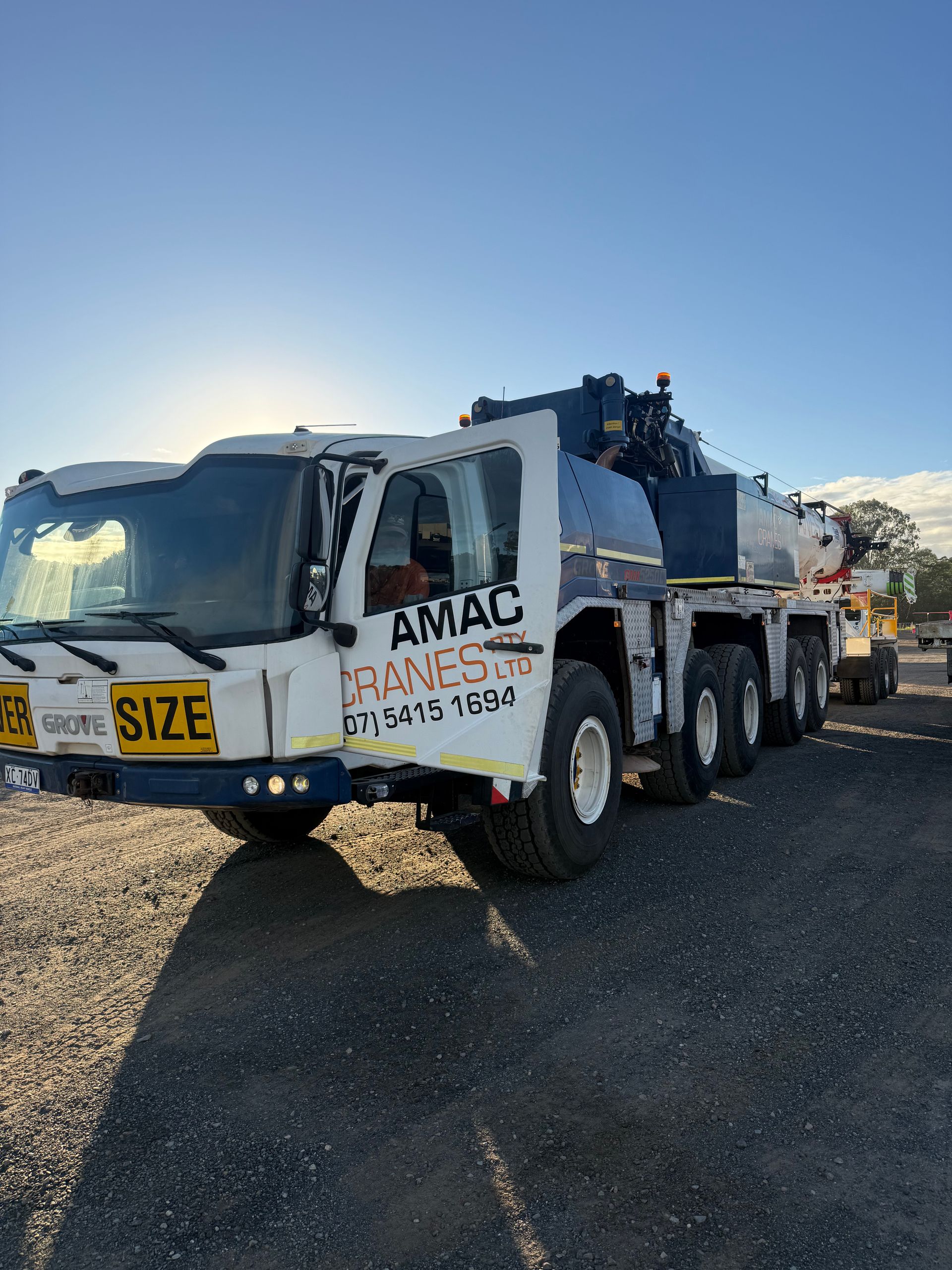 A Large Crane Is Sitting on Top of A Gravel Road at Sunset — AMAC Cranes in Coolum Beach, QLD
