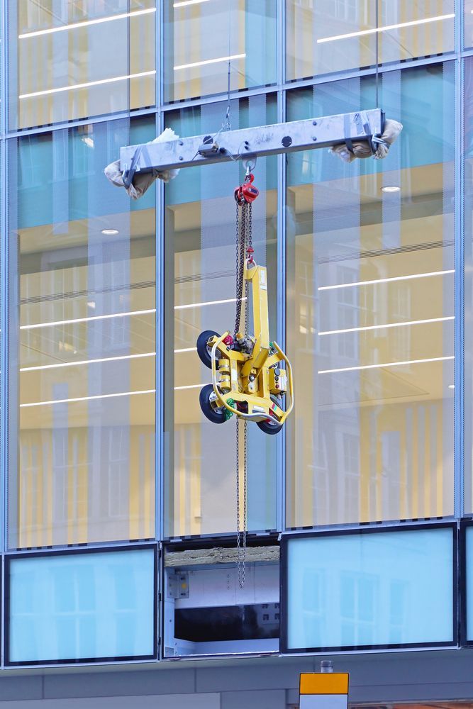 A Crane Is Lifting a Glass Window on A Building — AMAC Cranes in Coolum Beach, QLD
