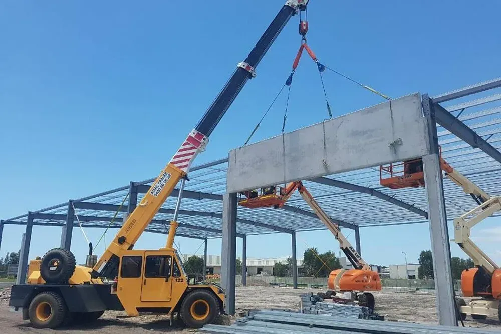 A Crane Is Lifting a Piece of Metal on A Construction Site — AMAC Cranes in North Lakes, QLD
