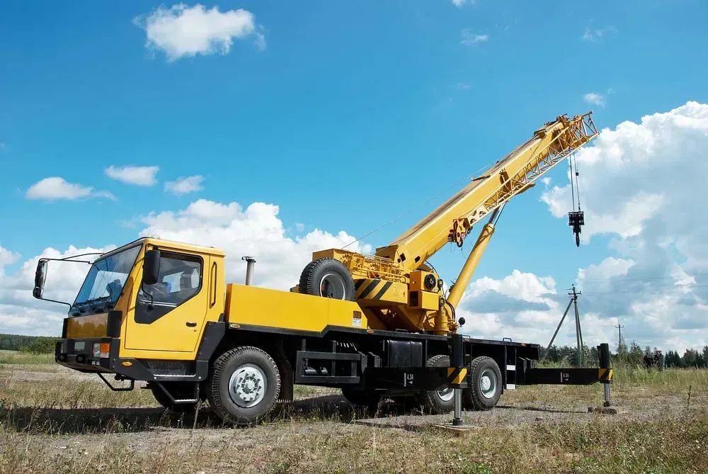A Yellow Truck with A Crane Attached to It Is Parked in A Field — AMAC Cranes in Coolum Beach, QLD