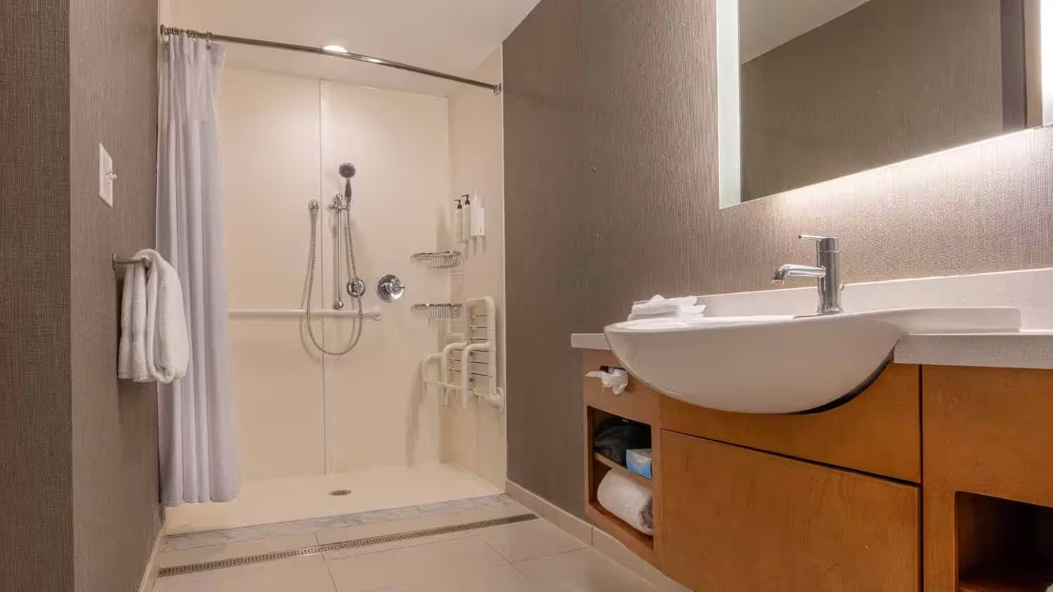 A bathroom with a sink , mirror and walk in shower.