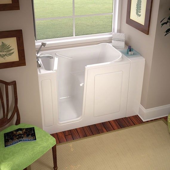 A walk in tub is in a bathroom next to a chair and a window.