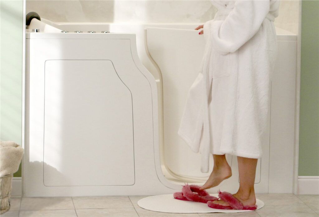 A woman in a bathrobe is standing in a walk in tub