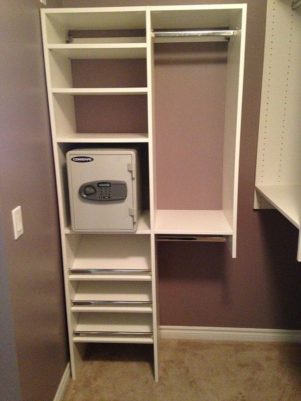 White closet organizer with shelves, hanging rods, drawers, and a small built-in safe in a bedroom closet.