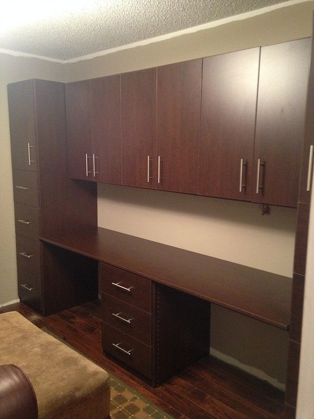 Wall-mounted dark wood cabinets and desk in a bedroom alcove with open shelving and drawers