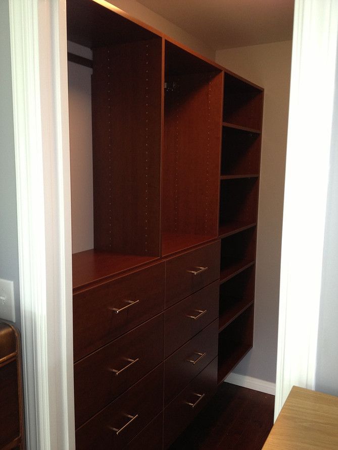 Empty dark wood walk-in closet with drawers, hanging space, and shelves.