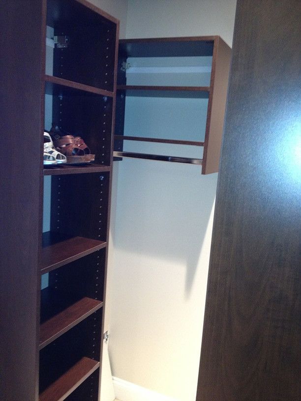 Open cabinet with dark shelves and a white door in a dimly lit room
