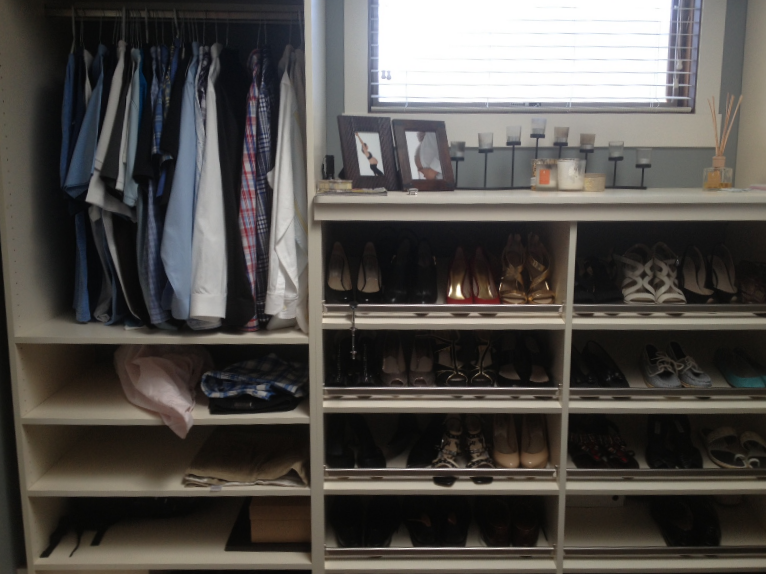Walk-in closet with hanging clothes, folded items, shoes, and framed photos on shelves