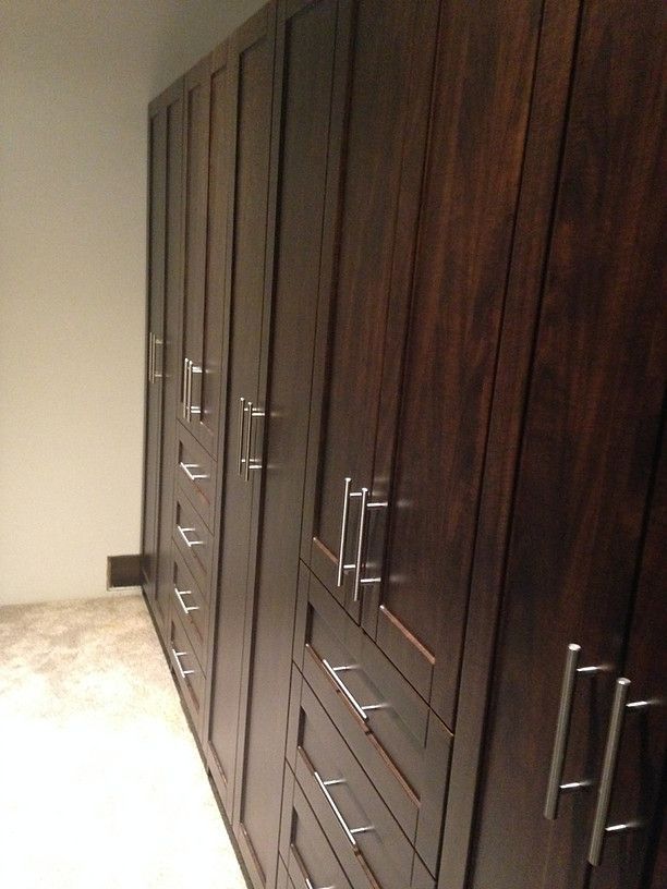 Row of dark wood wardrobes with silver handles along a hallway wall