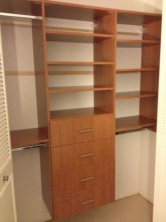Built-in wooden closet shelving with drawers and hanging rods in a room corner