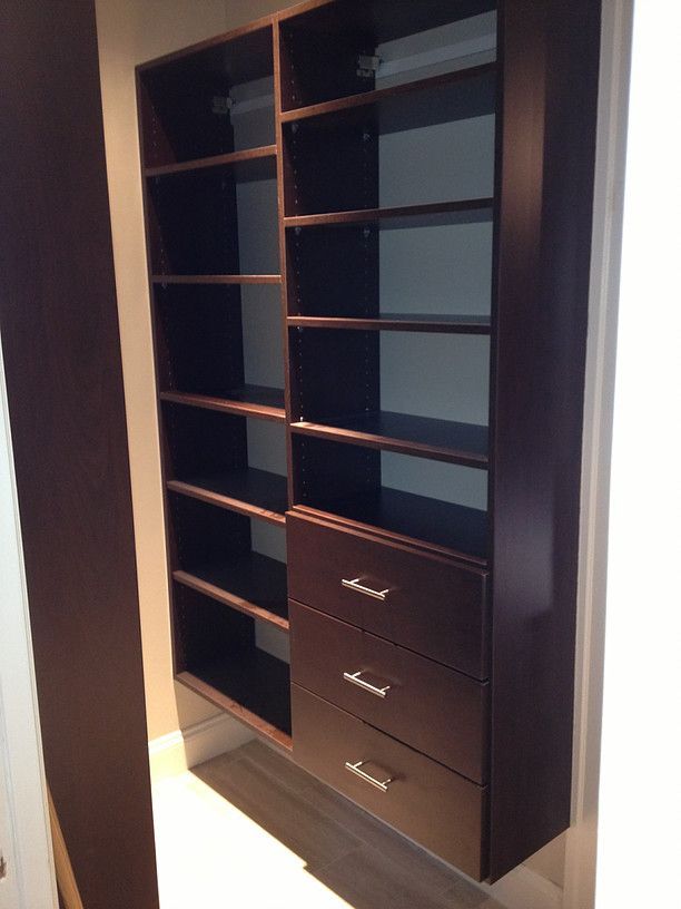 Open dark wood closet organizer with shelves and three drawers, viewed at an angle
